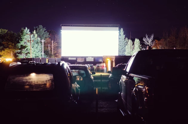 Fogged up cars parked at a drive-in movie theatre with blank screen